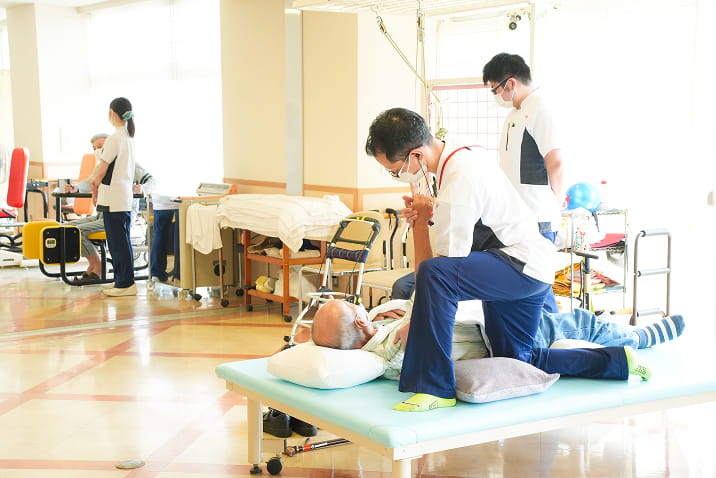 リハビリスタッフが利用者の脚のストレッチを支援する機能訓練の様子