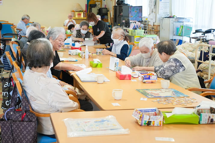 介護施設の広々としたリハビリテーション・レクリエーションスペース。自然光が差し込む明るく開放的な多目的ホール。高齢者の機能訓練や運動、大規模なレクリエーション活動に適した空間