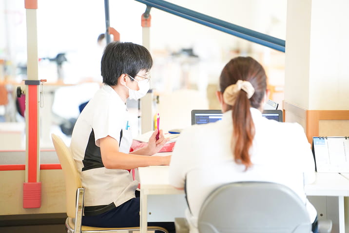 愛知県飛島村の医療法人良斉会ヴィラとびしまの個別リハビリテーション指導風景。介護スタッフが利用者と向き合い、リハビリテーション機器を使った個別カウンセリングや作業療法を行う様子